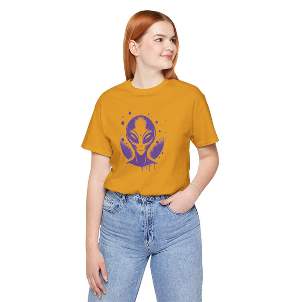 Woman wearing mustard yellow alien graphic streetwear t shirt and blue jeans looking sideways