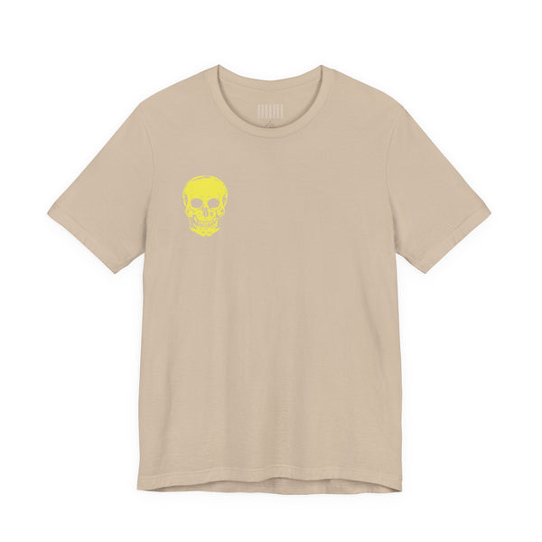 Beige t-shirt with a small yellow skull print on the front, underground style graphic tee.