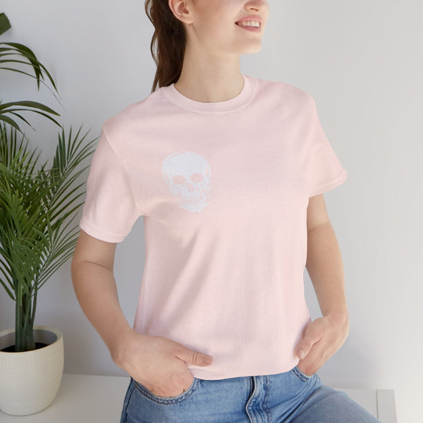 Woman wearing a light pink skull graphic t-shirt with a small white skull print on the front left chest paired with blue jeans