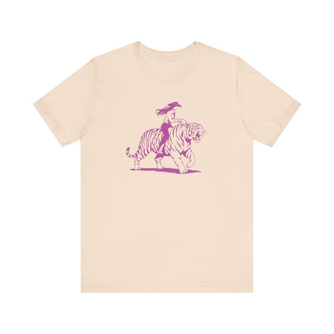 Beige unisex tee with neon magenta graphic of a cowgirl riding a tiger, retro humorous design
