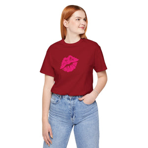 Woman wearing burgundy graphic tee with neon pink lip print and blue jeans