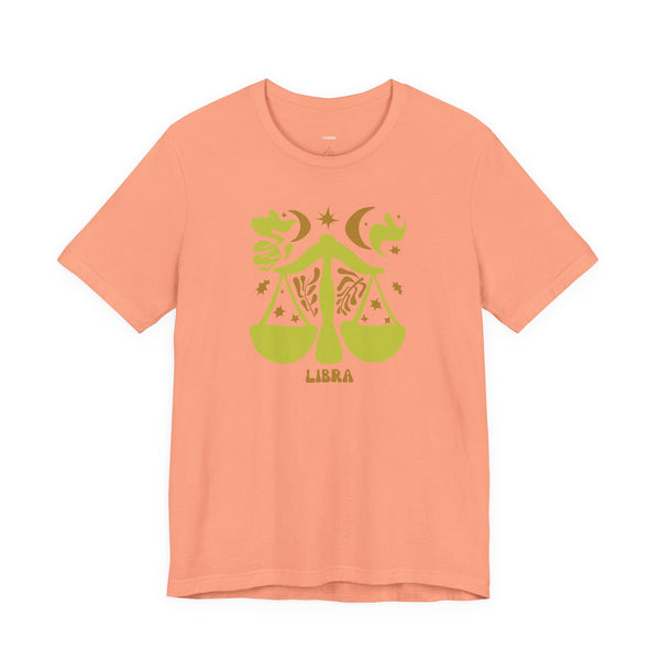 Peach Libra t shirt with green artistic zodiac balance scales, celestial stars, and moon graphic, unisex cotton tee.